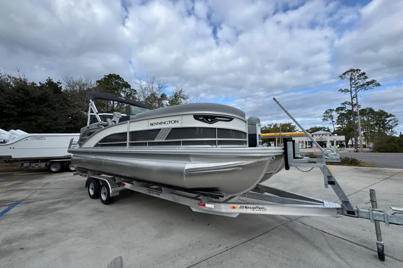 Slide: The Image of 2026 Bennington 24 MFB pontoon boat on trailer, parked outdoors under cloudy sky. - 7