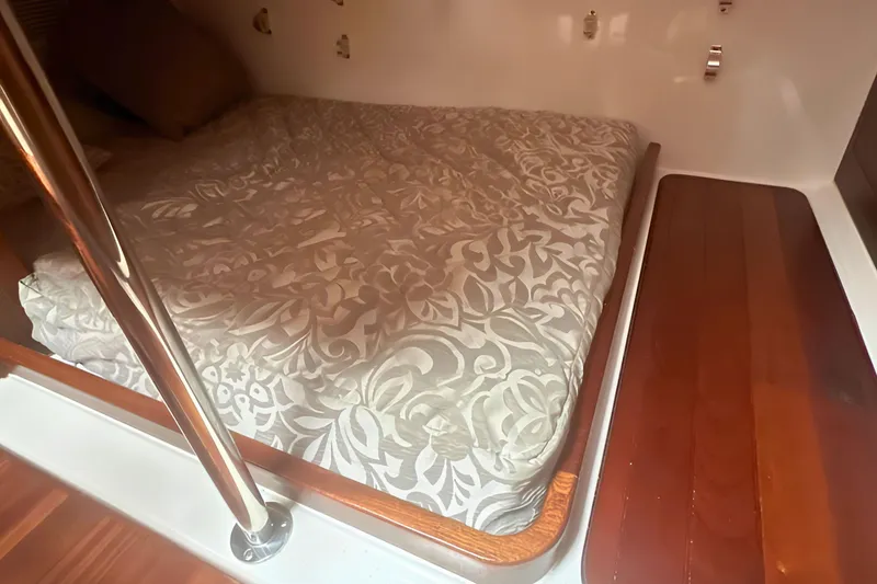 Slide: The Image of Cozy cabin interior of 2017 Pursuit OS 355 Offshore with patterned bedding and wooden flooring. - 12