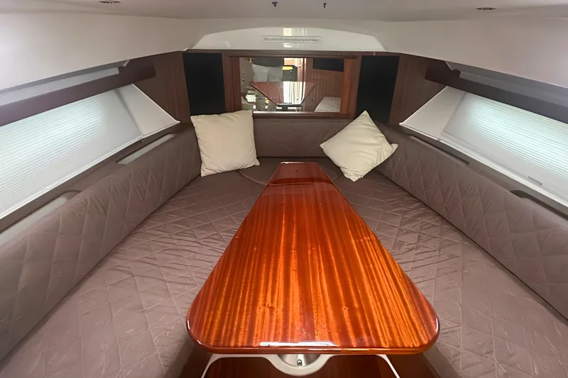 Slide: The Image of Interior of a 2017 Pursuit OS 355 Offshore boat with cushioned seating and wooden table. - 13