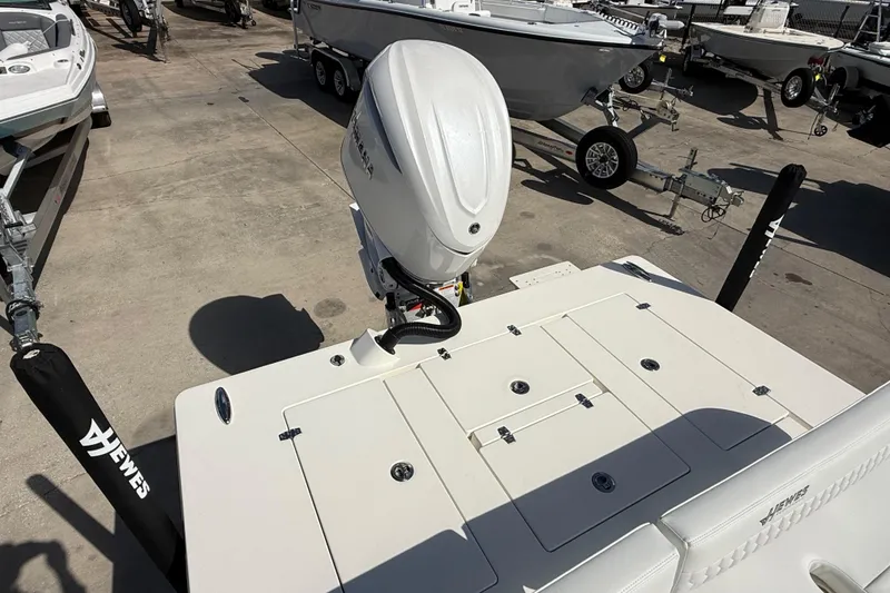 Slide: The Image of 2026 Hewes Redfisher 21 boat with outboard motor, displayed in a marina. - 7