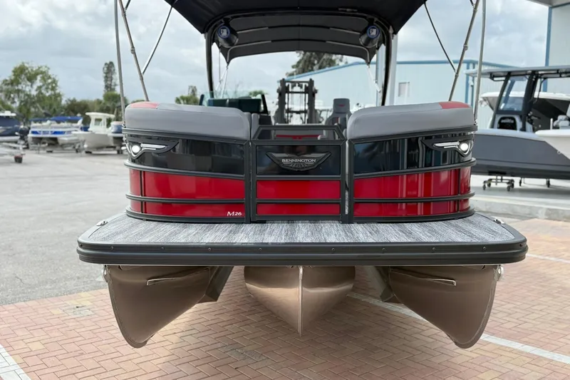 Slide: The Image of 2026 Bennington 26 M Center Swingback pontoon boat, red and black, docked on a sunny day. - 2