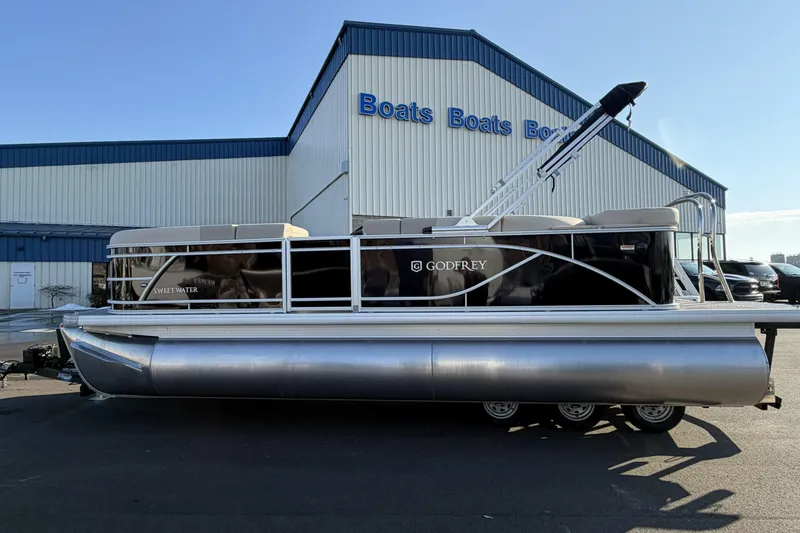 Slide: The Image of 2026 Godfrey Sweetwater 2086 C pontoon boat parked outside a boat dealership. - 4