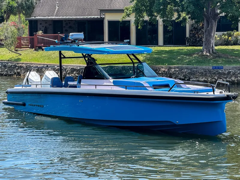Slide: The Image of 2025 Axopar 37 Sun Top BRABUS Trim boat in vibrant blue on a calm waterway. - 3