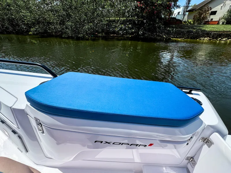 Slide: The Image of 2025 Axopar 37 Sun Top BRABUS Trim boat with blue seating by a river. - 14