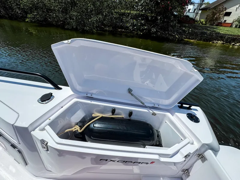 Slide: The Image of 2025 Axopar 37 Sun Top BRABUS Trim storage compartment open by the water. - 15