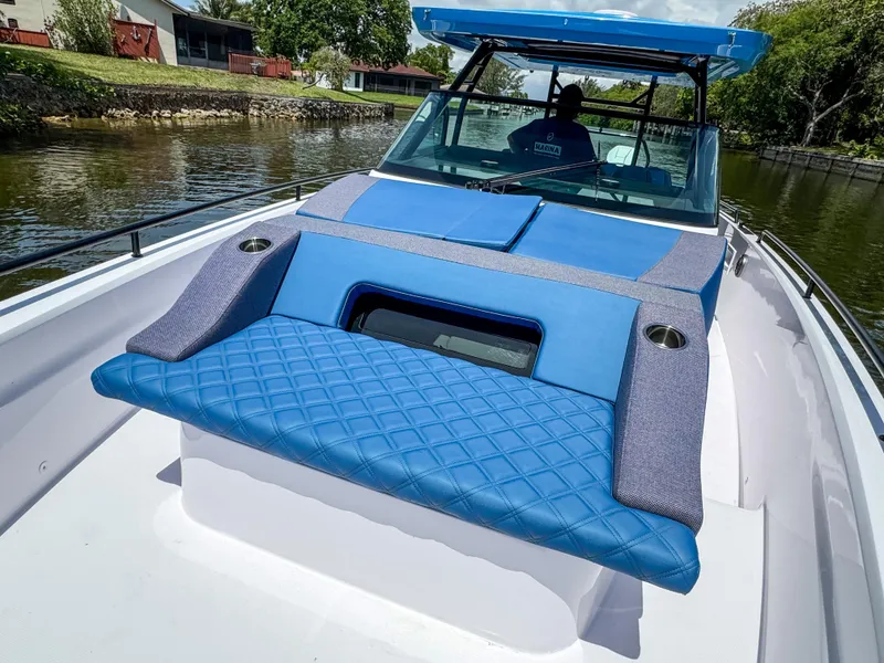 Slide: The Image of 2025 Axopar 37 Sun Top BRABUS Trim with blue seating on a calm waterway. - 27