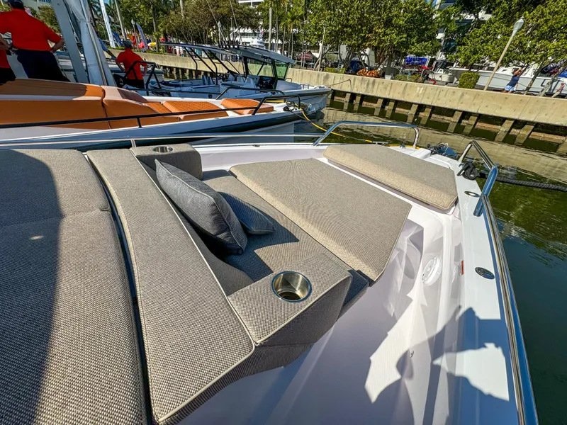 Slide: The Image of 2024 Axopar 37XC CROSS CABIN boat with cushioned seating and cup holders, docked by the water. - 16