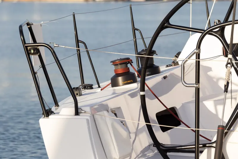 Slide: The Image of 2008 J Boats J/122 sailboat deck with winch and steering wheel, docked on calm water. - 5