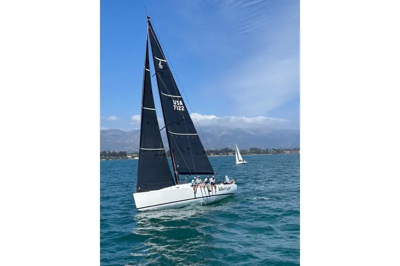 Slide: The Image of Sailing yacht J/122 from 2008 on the water with crew, mountainous backdrop. - 56