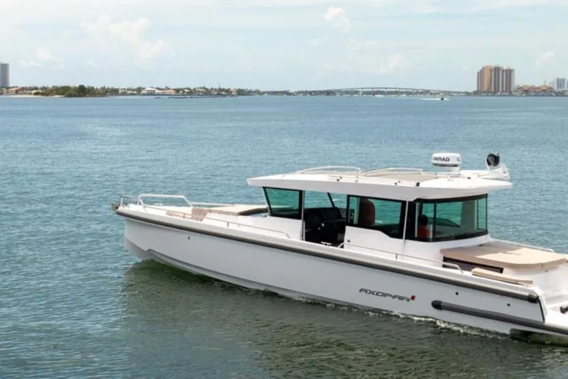 Slide: The Image of 2024 Axopar 37XC CROSS CABIN cruising on a calm, scenic waterway. - 5