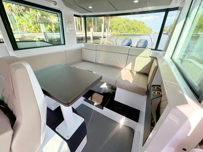 Slide: The Image of 2024 Axopar 37XC CROSS CABIN interior with seating and table, overlooking water. - 14