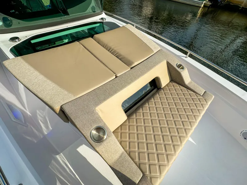 Slide: The Image of Luxurious sunbed on 2024 Axopar 37XC CROSS CABIN, featuring beige cushions and diamond-patterned upholstery. - 11