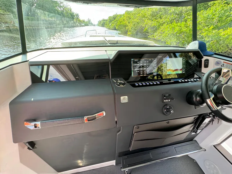 Slide: The Image of 2024 Axopar 37XC CROSS CABIN helm with modern controls and scenic waterway view. - 12