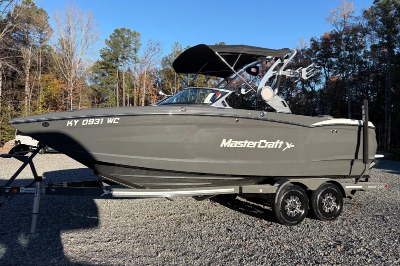 The Image of 2019 MasterCraft XStar boat on trailer, parked outdoors with trees in background. - 1