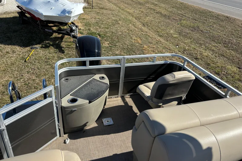 Slide: The Image of 2024 Sun Tracker Fishin' Barge 20 DLX interior with seating and console, parked on grass. - 62