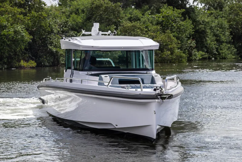 Slide: The Image of 2024 Axopar 37XC CROSS CABIN cruising on a serene waterway. - 26