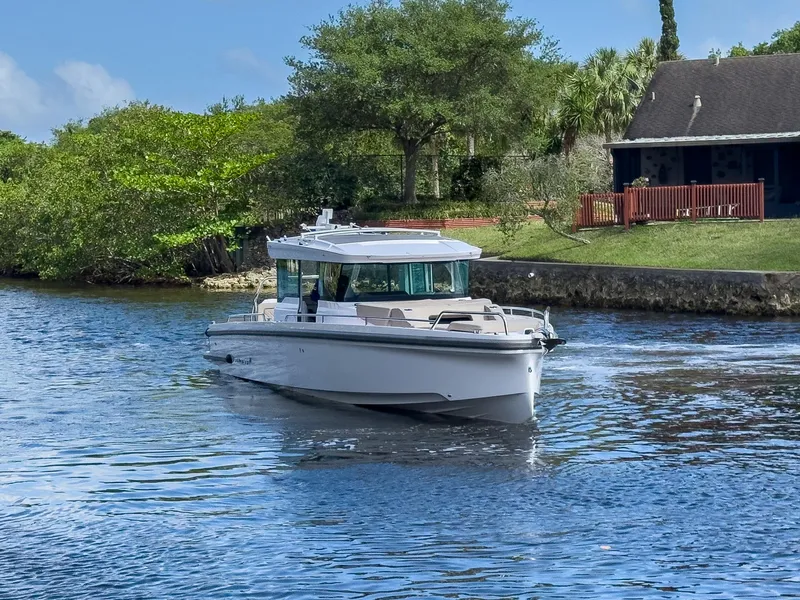 Slide: The Image of 2024 Axopar 37XC CROSS CABIN boat cruising on a serene river near a house. - 39