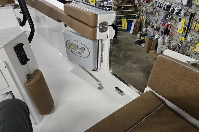 Slide: The Image of 2025 Sea Hunt Ultra 255 SE boat interior with tan seating in a workshop. - 11