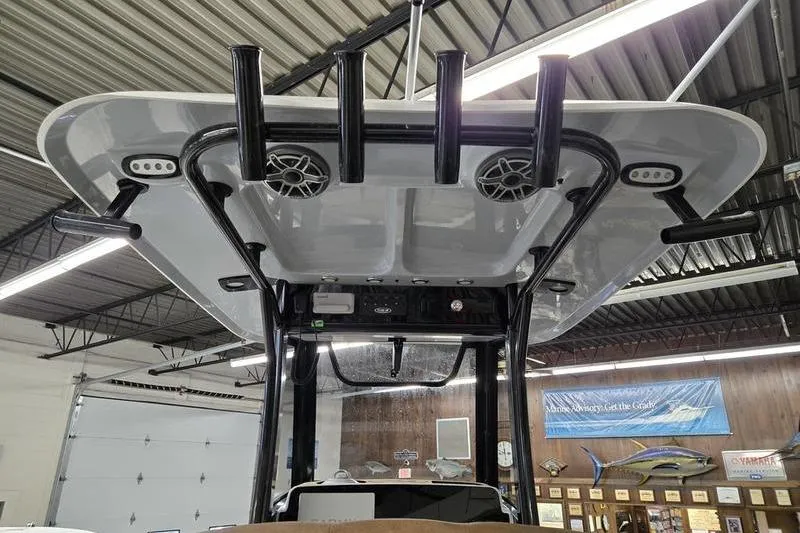 Slide: The Image of 2025 Sea Hunt Ultra 255 SE boat top view with rod holders and speakers in a showroom. - 8