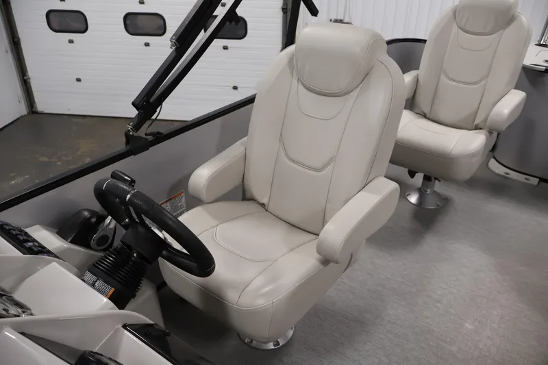Slide: The Image of 2021 Sylvan 8522 Mirage boat interior with beige captain chairs and steering wheel. - 28