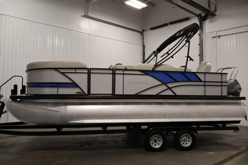 Slide: The Image of 2021 Sylvan 8522 Mirage pontoon boat on trailer in indoor storage. - 8