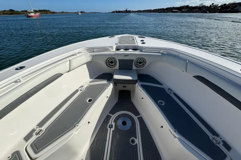 Slide: The Image of 2020 Tidewater 280 CC Adventure boat interior with seating and storage, on calm water. - 18