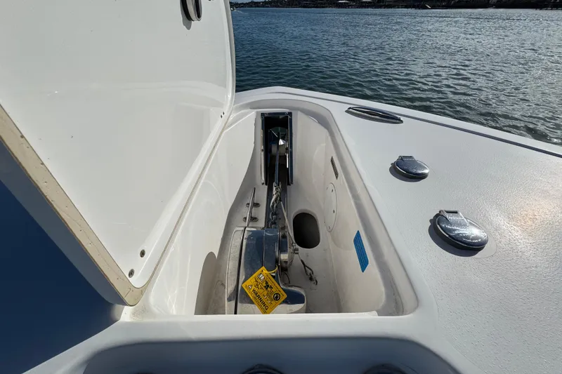 Slide: The Image of Open anchor compartment on 2020 Tidewater 280 CC Adventure boat, with visible chain and warning label. - 21