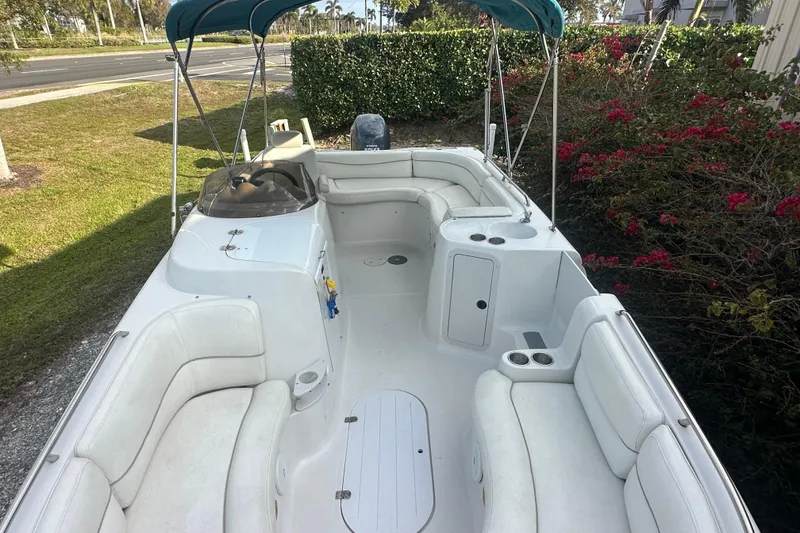 Slide: The Image of 2004 Vectra S-215 boat with white seating and canopy, parked near greenery. - 4