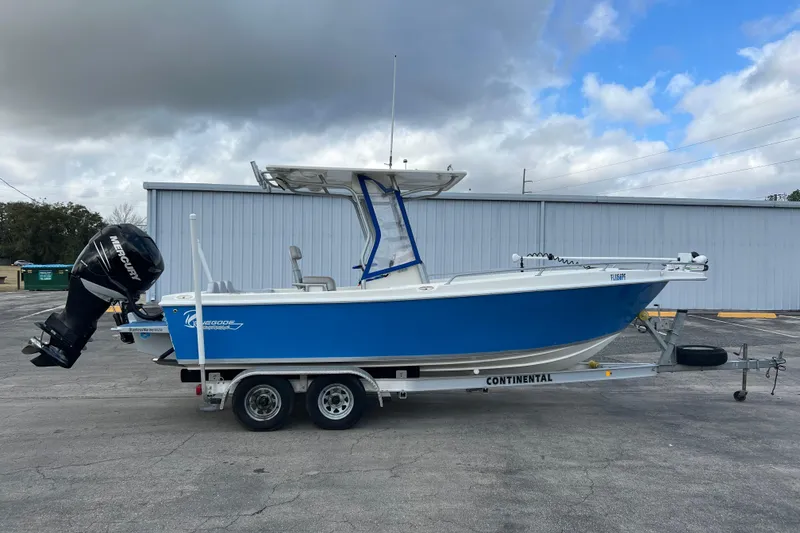 The Image of 2011 Renegade OF 23 boat on trailer, blue hull, outboard motor, cloudy sky background. - 1