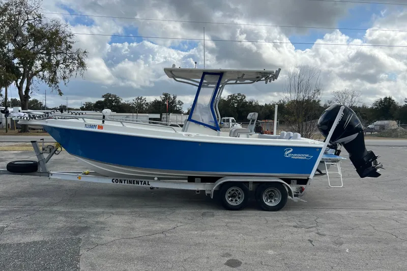 Slide: The Image of 2011 Renegade OF 23 boat on trailer, blue hull, parked outdoors under cloudy sky. - 5