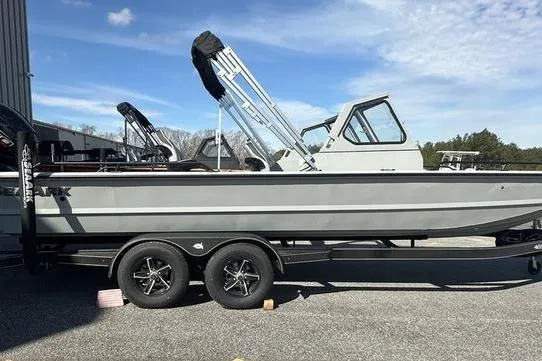 The Image of 2025 SeaArk ProCat 240 boat on trailer, side view, under clear blue sky. - 0