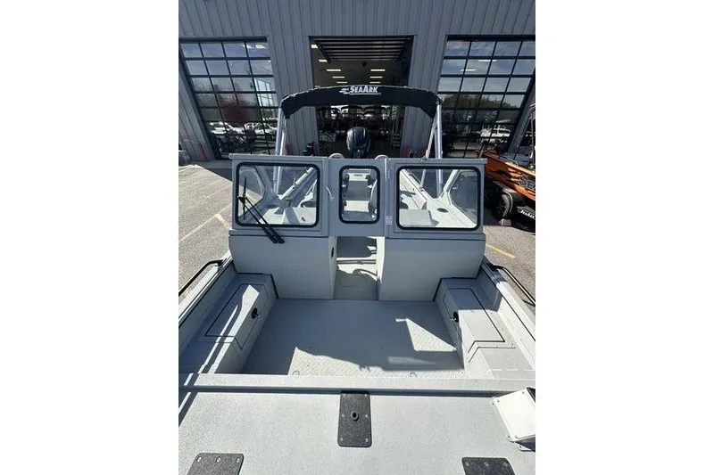 Slide: The Image of 2025 SeaArk ProCat 240 boat interior, featuring spacious deck and windshield, parked outside showroom. - 7