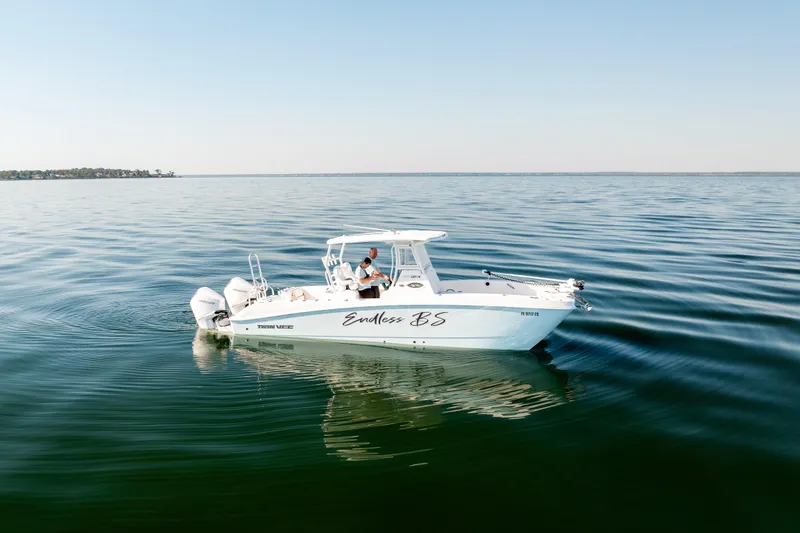 Slide: The Image of 2023 Twin Vee 260 GFX CC boat cruising on calm waters under clear skies. - 1