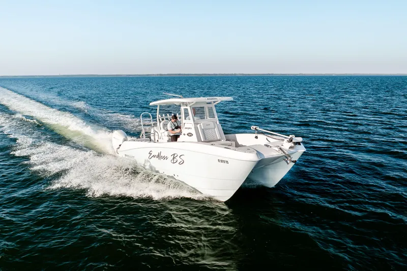 Slide: The Image of 2023 Twin Vee 260 GFX CC boat cruising on open water, clear sky background. - 24