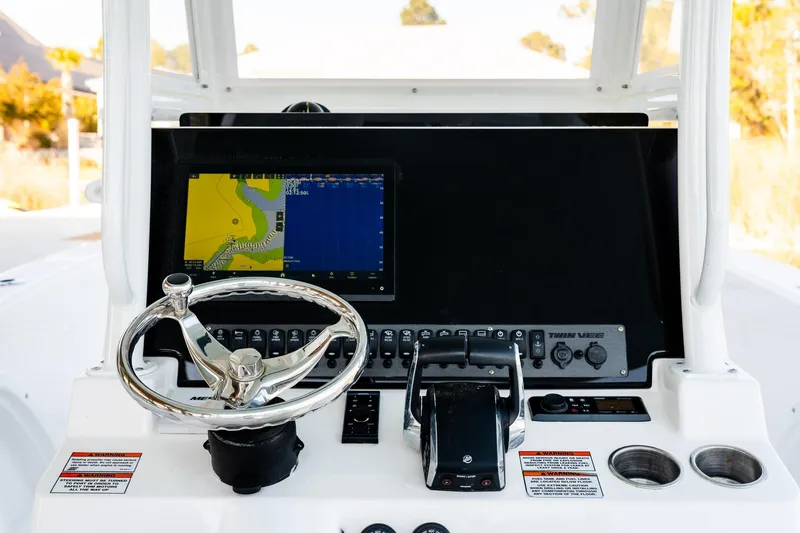 Slide: The Image of 2023 Twin Vee 260 GFX CC boat dashboard with steering wheel and navigation display. - 50