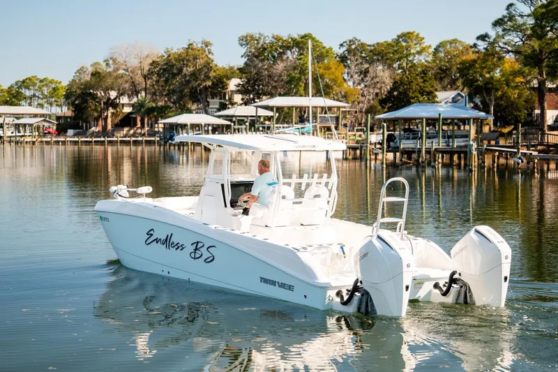 Slide: The Image of 2023 Twin Vee 260 GFX CC boat cruising on a calm lake with scenic background. - 52