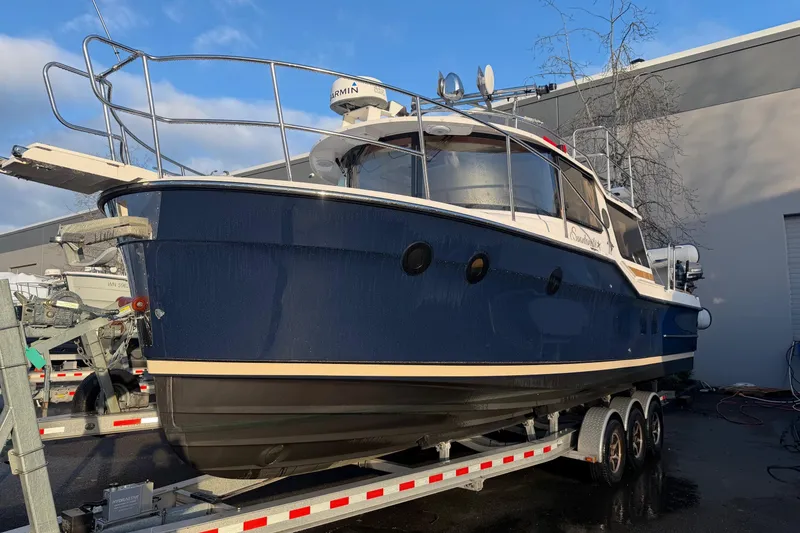 The Image of 2024 Ranger Tugs R-29 CB boat on trailer, blue hull, docked outdoors. - 1