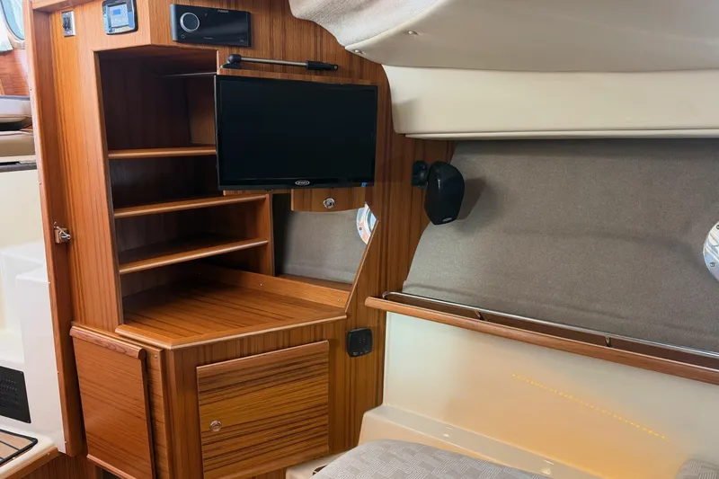 Slide: The Image of 2024 Ranger Tugs R-29 CB interior with wooden cabinetry and mounted TV. - 18