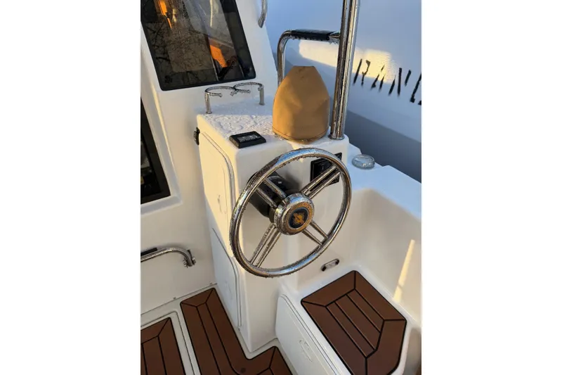 Slide: The Image of 2024 Ranger Tugs R-29 CB helm with polished steering wheel and teak flooring. - 3