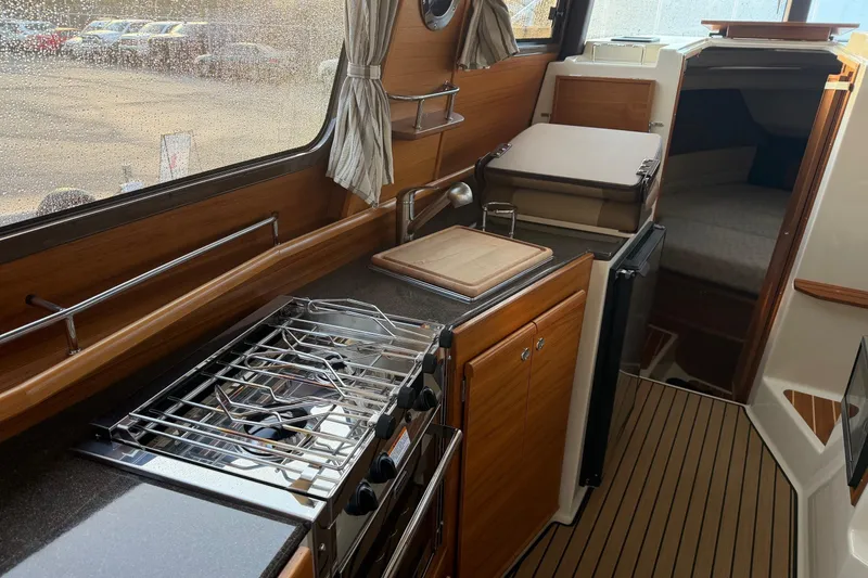 Slide: The Image of 2024 Ranger Tugs R-29 CB interior kitchen with stove, sink, and wooden cabinetry. - 9