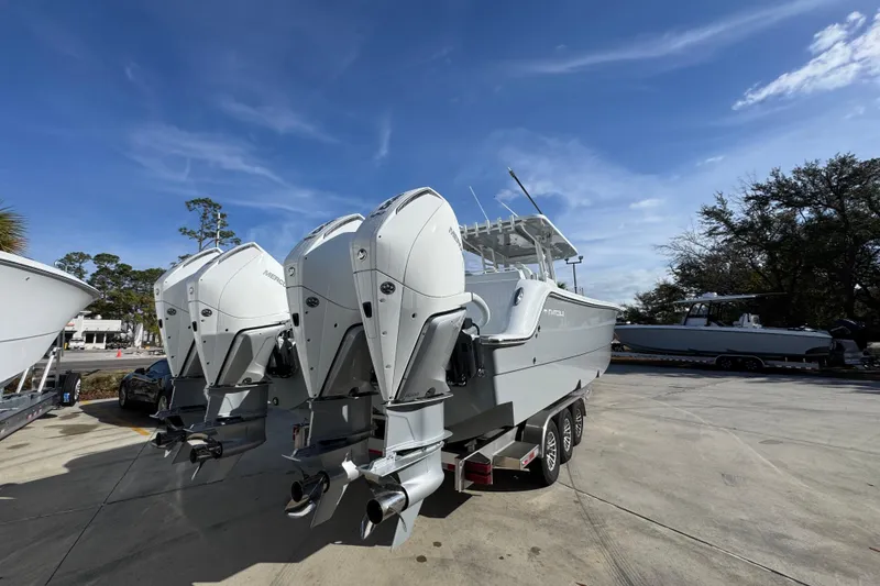 Slide: The Image of 2026 Invincible 36 Catamaran with triple outboard engines on a trailer under a clear sky. - 14