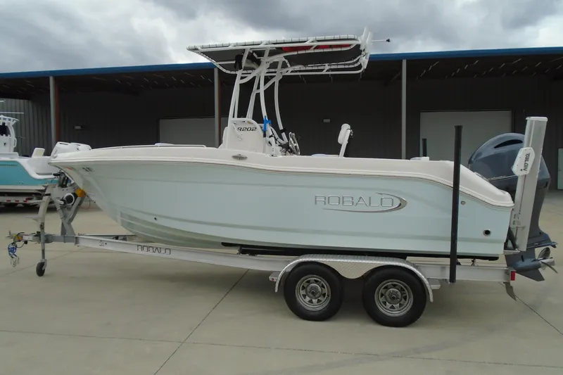 Slide: The Image of 2021 Robalo R202 Explorer boat on trailer, parked outdoors under cloudy sky. - 1