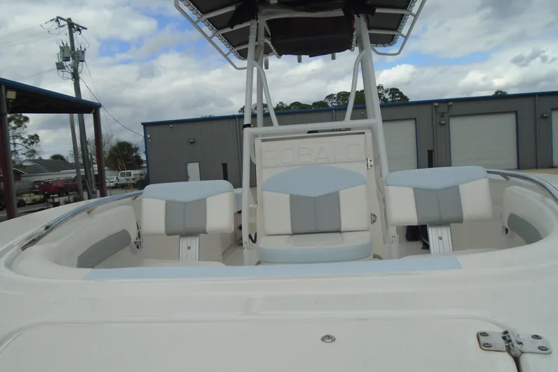 Slide: The Image of 2021 Robalo R202 Explorer boat with cushioned seating, docked outdoors under cloudy skies. - 27