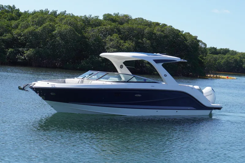Slide: The Image of 2020 Sea Ray SLX 310 Outboard boat cruising on calm water near lush greenery. - 2