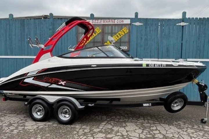 The Image of 2018 Yamaha Boats 212X on trailer, black and white design, red accents, parked outdoors. - 0