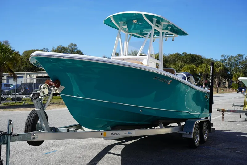 Slide: The Image of 2021 Sea Hunt Ultra 219 boat on trailer, vibrant teal color, parked outdoors. - 2