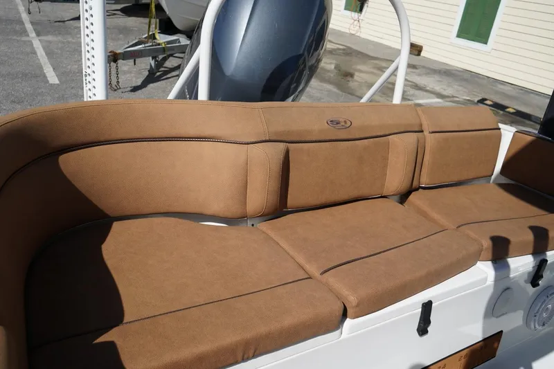 Slide: The Image of 2021 Sea Hunt Ultra 219 boat with tan cushioned seating in sunlight. - 40