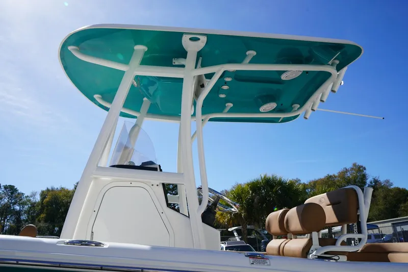 Slide: The Image of 2021 Sea Hunt Ultra 219 boat with teal T-top and seating, under clear blue sky. - 6