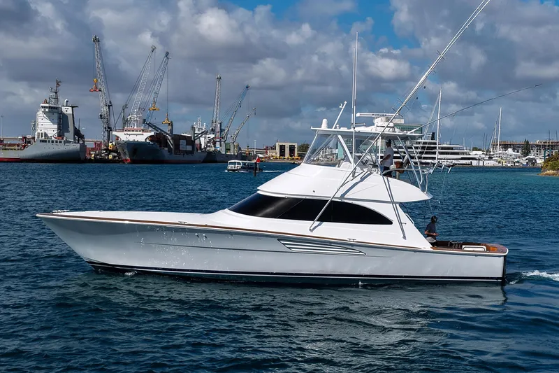 The Image of 2026 Viking 54 Convertible yacht cruising in a busy harbor with cranes and ships. - 0