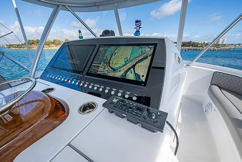 Slide: The Image of Helm of 2026 Viking 54 Convertible yacht with advanced navigation system, overlooking serene waters. - 18